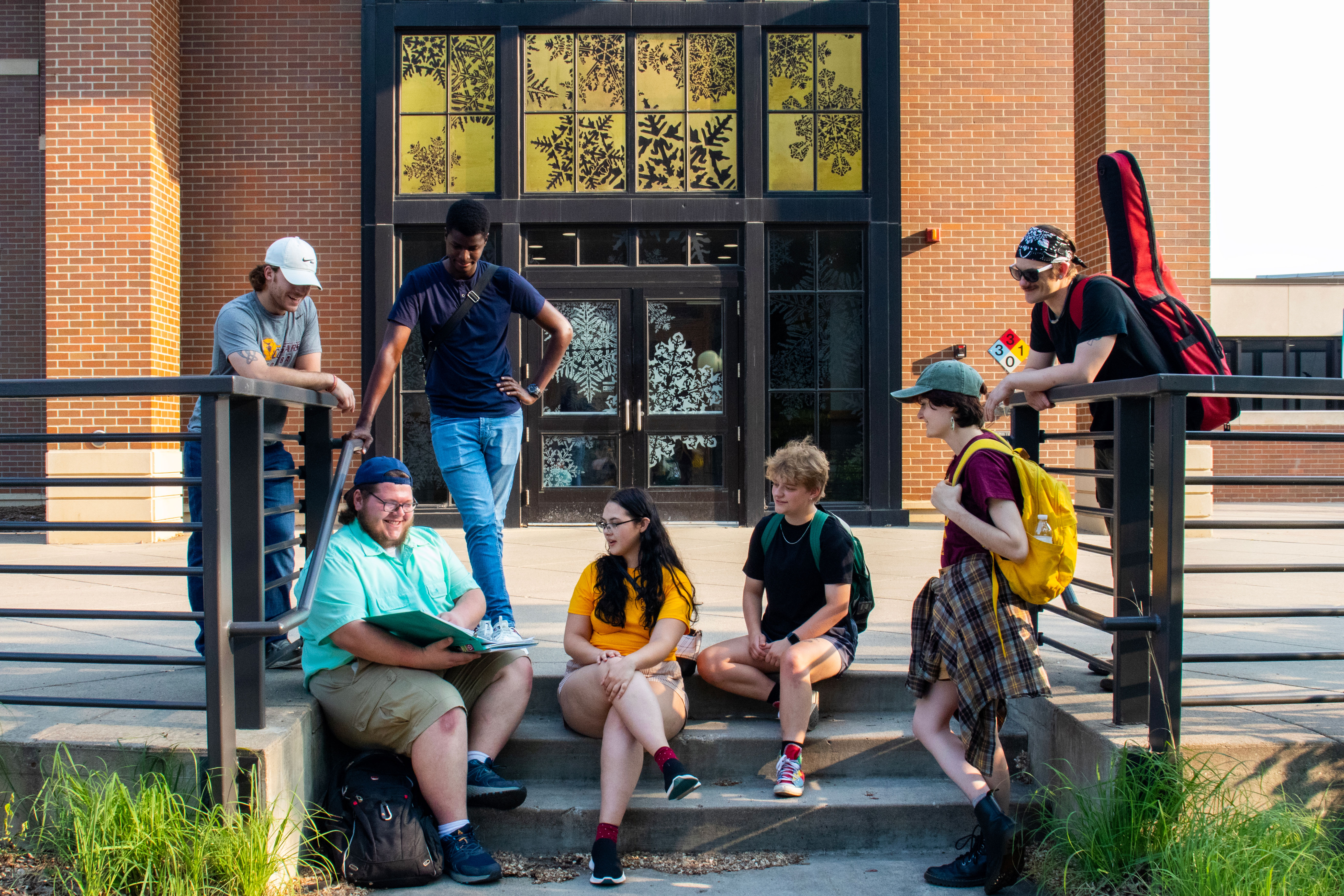 A group of students hangs out on the steps in front of the Science Building on a summer evening.