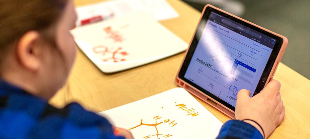 student looks at organic chemistry problems on a tablet