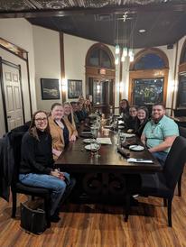A group of people at a long table in a restaurant. 