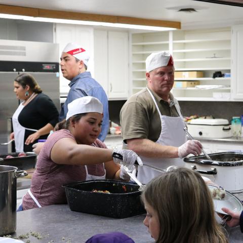 Four people in a commercial kitchen serving food